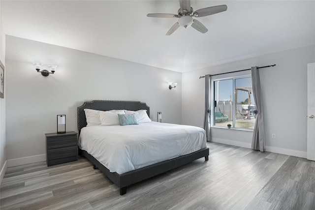 bedroom featuring lofted ceiling, light wood finished floors, and baseboards