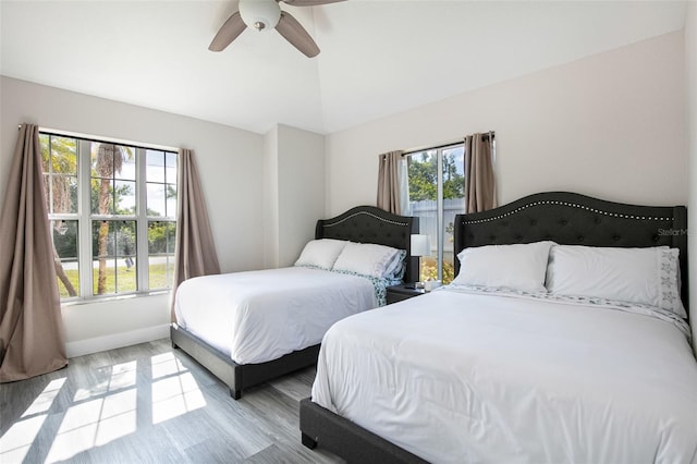 bedroom with ceiling fan, lofted ceiling, light wood-style floors, and baseboards
