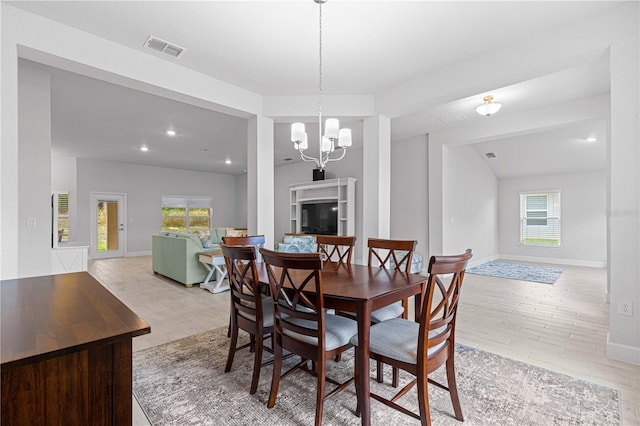 dining space with a wealth of natural light, a notable chandelier, light hardwood / wood-style floors, and lofted ceiling