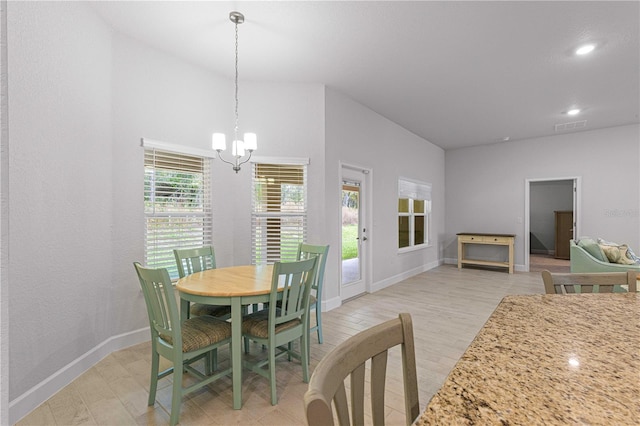 dining area with light hardwood / wood-style flooring and an inviting chandelier