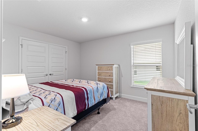 bedroom with a textured ceiling, light carpet, and a closet