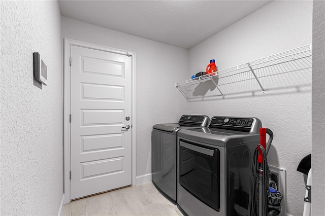 clothes washing area featuring a textured ceiling, light hardwood / wood-style flooring, and independent washer and dryer