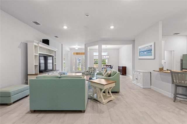 living room with a textured ceiling, light hardwood / wood-style floors, and a chandelier