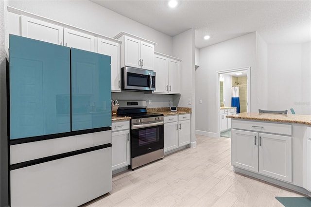 kitchen with white cabinetry, a textured ceiling, light stone counters, and stainless steel appliances