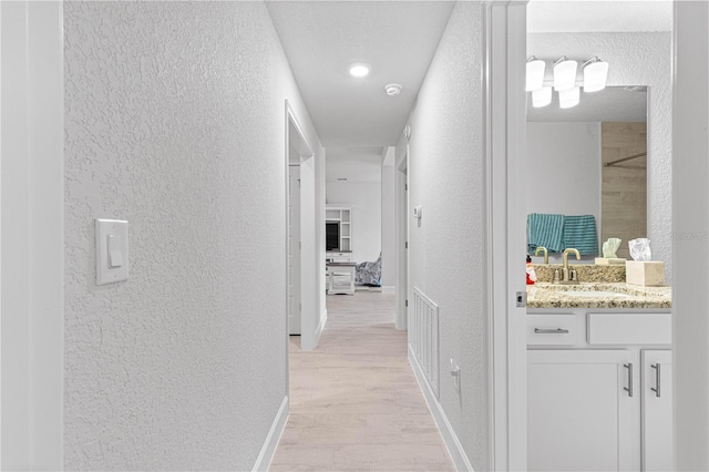 hallway with light hardwood / wood-style flooring and sink