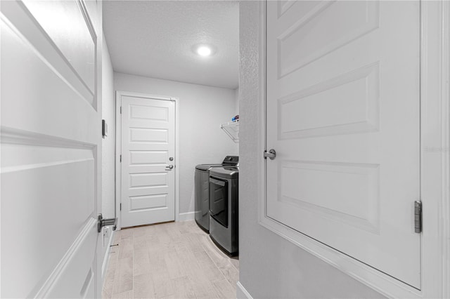 laundry area featuring separate washer and dryer, a textured ceiling, and light wood-type flooring