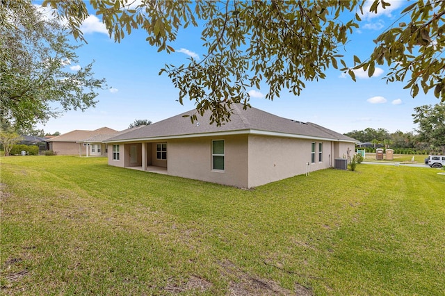 back of property with central AC unit and a lawn