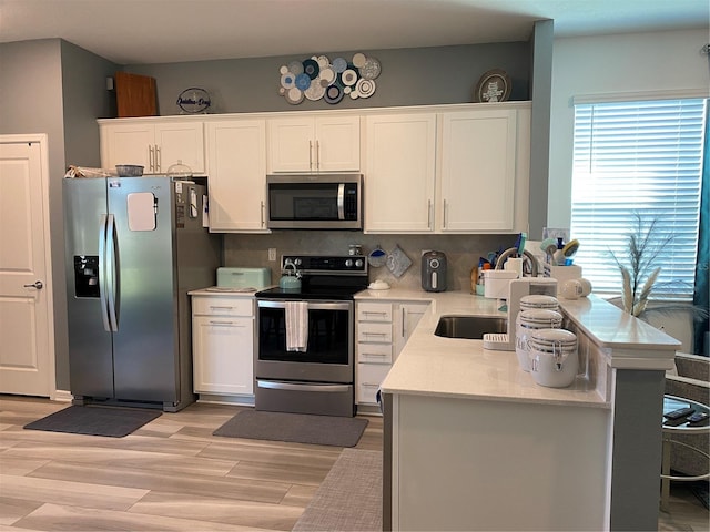 kitchen featuring white cabinets, decorative backsplash, light hardwood / wood-style flooring, and appliances with stainless steel finishes