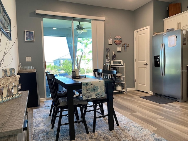 dining space with ceiling fan and light hardwood / wood-style flooring