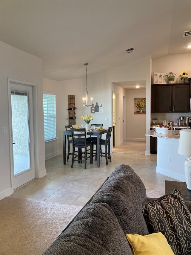 dining area with a wealth of natural light, an inviting chandelier, lofted ceiling, and light tile patterned flooring