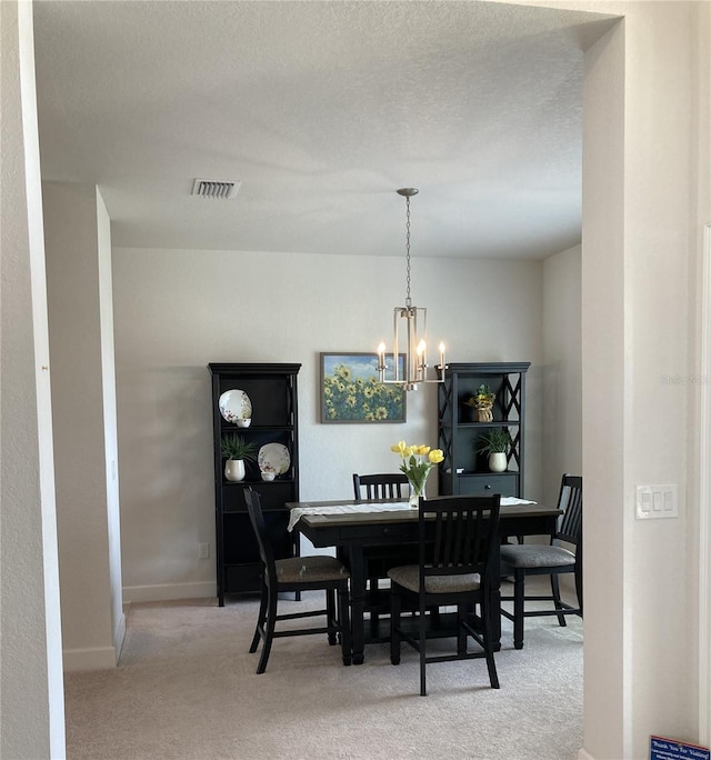 dining space featuring a textured ceiling, light colored carpet, and a chandelier