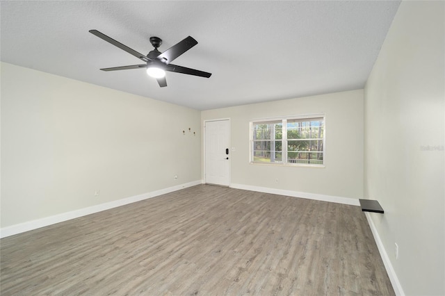 empty room featuring ceiling fan, light wood-type flooring, and a textured ceiling