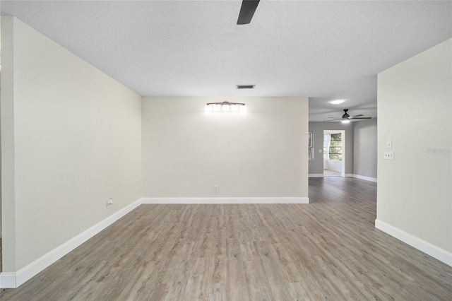 spare room with ceiling fan, wood-type flooring, and a textured ceiling