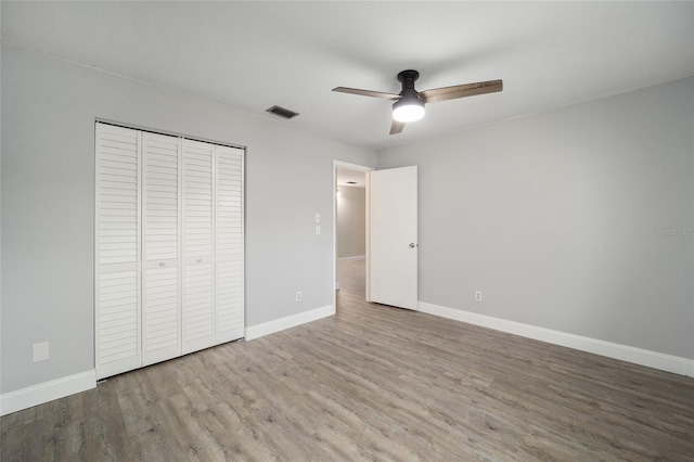 unfurnished bedroom featuring ceiling fan, a closet, and wood-type flooring