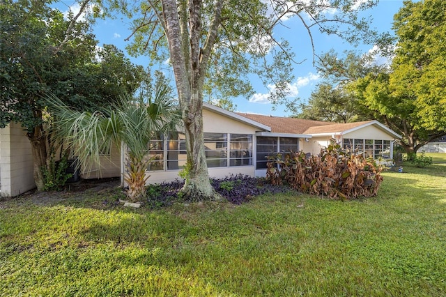 back of property featuring a sunroom and a lawn