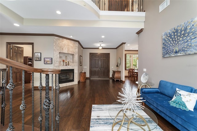 living room featuring dark hardwood / wood-style flooring, crown molding, and a tile fireplace