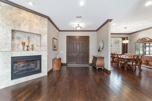 entrance foyer with crown molding, dark wood-type flooring, and a tile fireplace