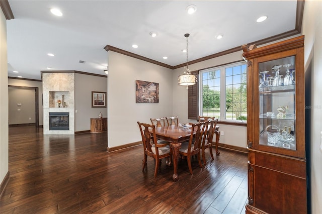 dining room featuring a tile fireplace, crown molding, and dark wood-type flooring