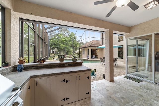 interior space featuring tile countertops, white cabinetry, ceiling fan, and a healthy amount of sunlight