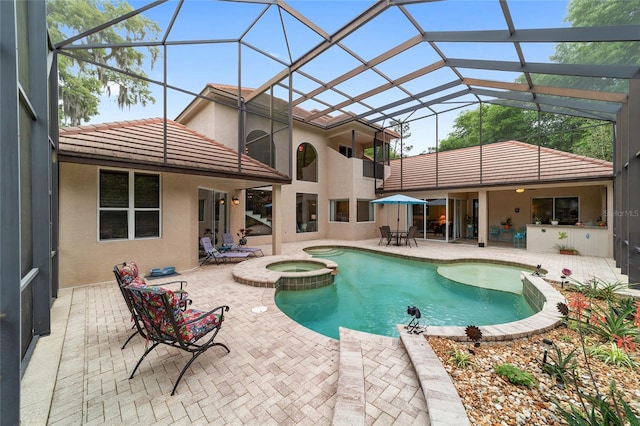 view of swimming pool with glass enclosure, an in ground hot tub, and a patio