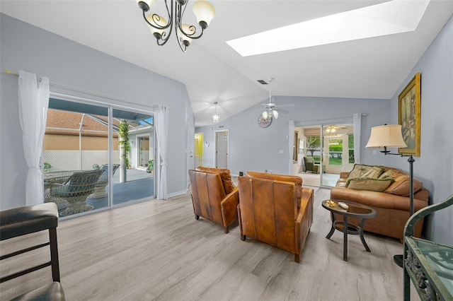 living room with vaulted ceiling with skylight, light hardwood / wood-style floors, and ceiling fan with notable chandelier