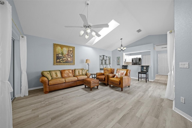 living room featuring ceiling fan with notable chandelier, light hardwood / wood-style flooring, and lofted ceiling with skylight