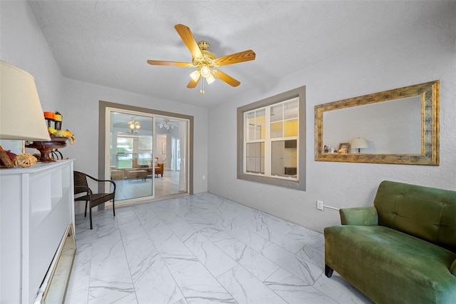 living area with ceiling fan and a textured ceiling