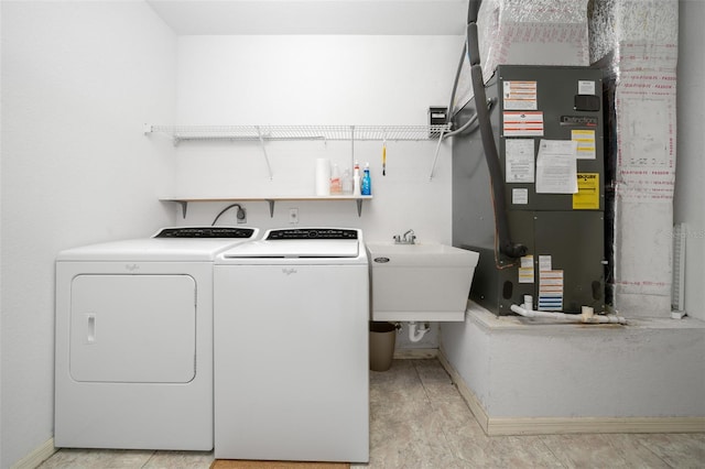 laundry room with heating unit, washer and clothes dryer, and sink