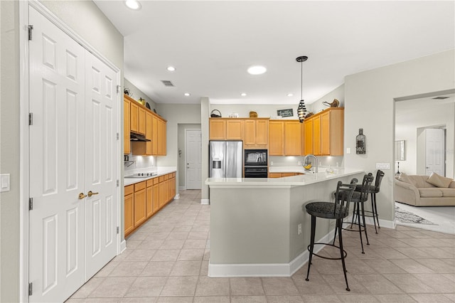 kitchen featuring a breakfast bar, black appliances, kitchen peninsula, light tile patterned floors, and pendant lighting