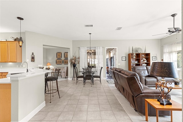 tiled living room with sink and ceiling fan with notable chandelier