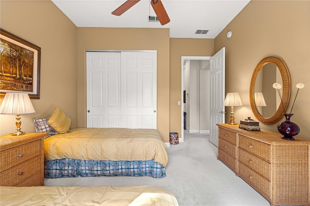 bedroom with ceiling fan, light carpet, and a closet