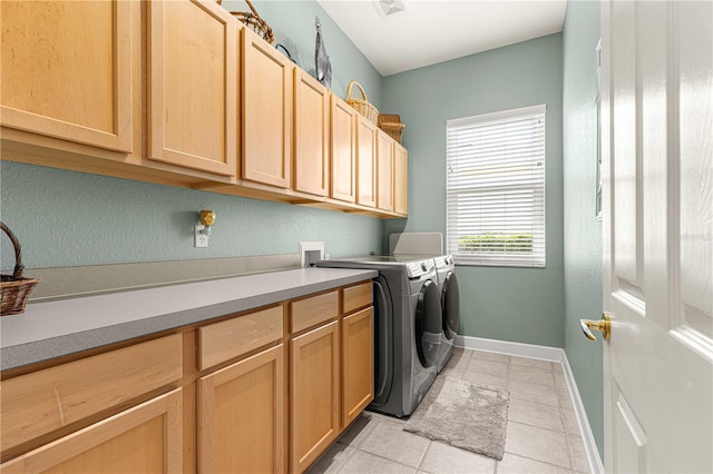 laundry area with washing machine and dryer, cabinets, and light tile patterned flooring