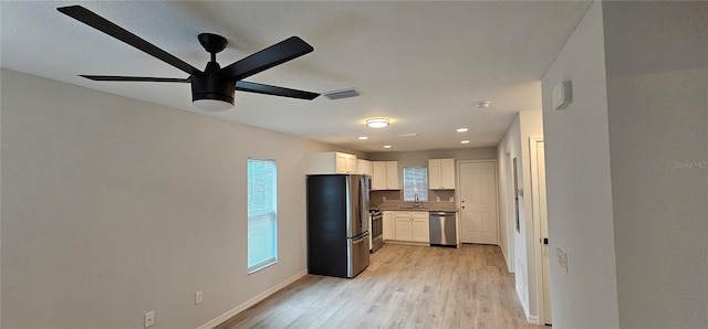 kitchen featuring stainless steel appliances, light hardwood / wood-style floors, sink, backsplash, and white cabinets