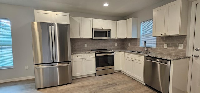 kitchen featuring appliances with stainless steel finishes, sink, light stone counters, and white cabinets