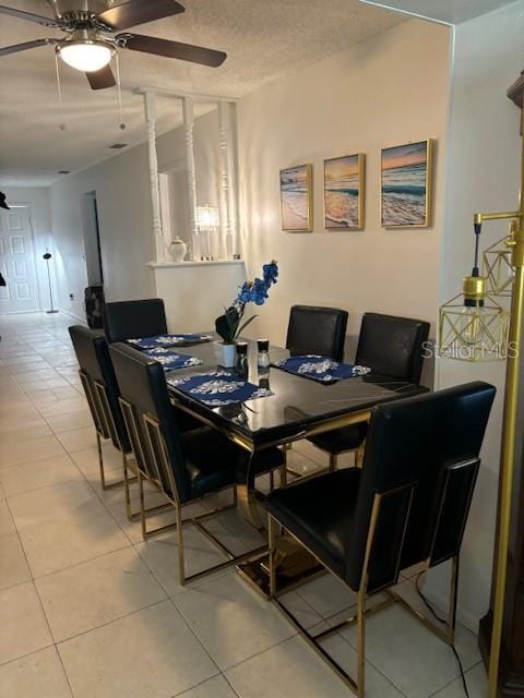 tiled dining space with a textured ceiling and ceiling fan