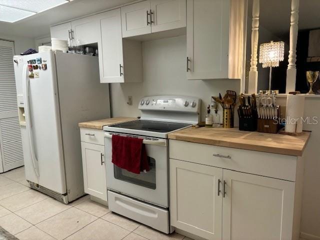 kitchen with white cabinets, light tile patterned floors, white appliances, and wooden counters