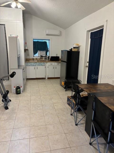 kitchen with white cabinetry, ceiling fan, a textured ceiling, lofted ceiling, and black refrigerator