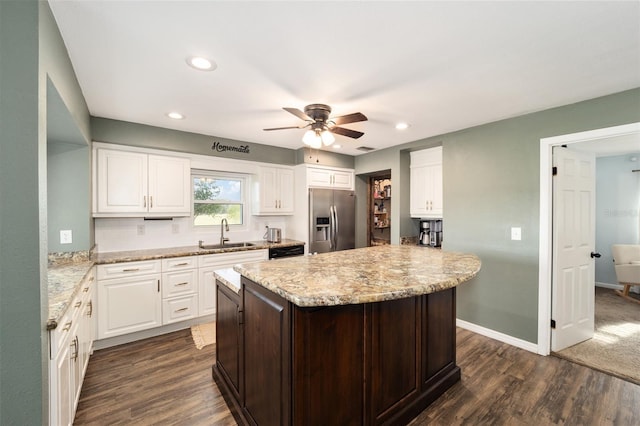 kitchen with stainless steel fridge, a kitchen island, white cabinetry, dark hardwood / wood-style floors, and sink