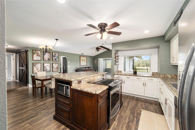 kitchen featuring stainless steel appliances, white cabinetry, vaulted ceiling, a barn door, and dark hardwood / wood-style flooring