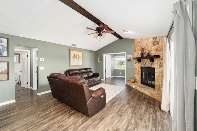 living room with dark hardwood / wood-style flooring, ceiling fan, a stone fireplace, and lofted ceiling with beams