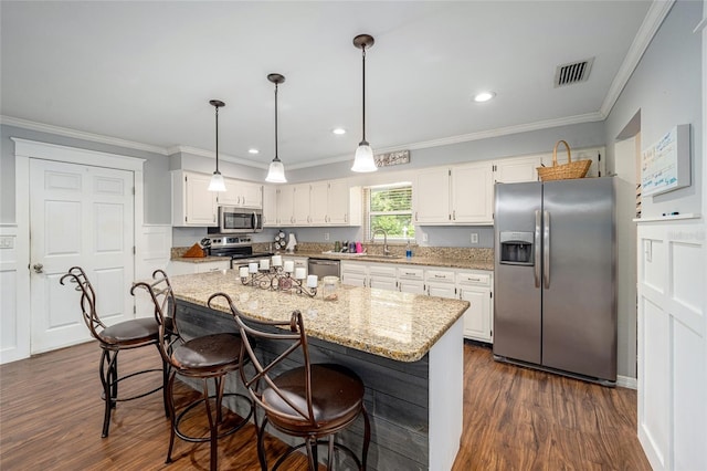 kitchen featuring appliances with stainless steel finishes, dark wood-type flooring, sink, white cabinets, and a kitchen island