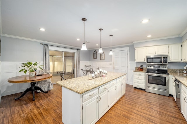 kitchen with appliances with stainless steel finishes, a center island, decorative light fixtures, and white cabinetry