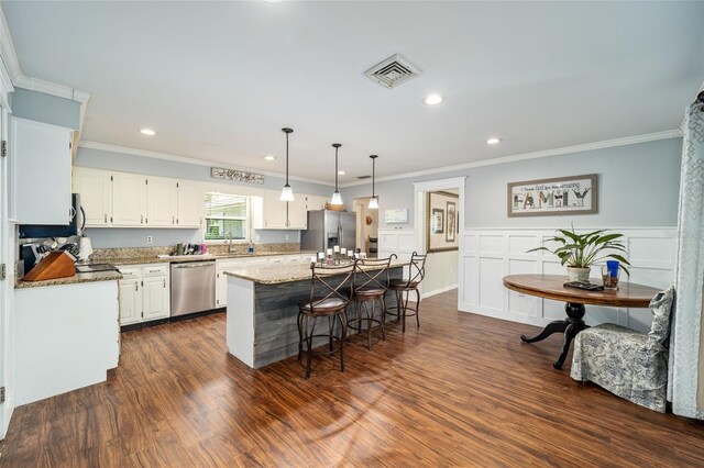 kitchen with light stone countertops, white cabinetry, a center island, dark wood-type flooring, and appliances with stainless steel finishes