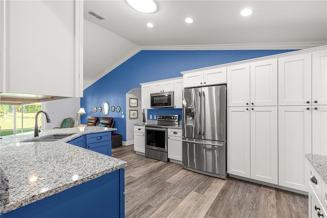 kitchen featuring stainless steel appliances, white cabinetry, light wood-type flooring, and vaulted ceiling