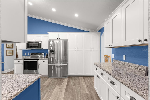 kitchen featuring stainless steel appliances, vaulted ceiling, white cabinets, and crown molding