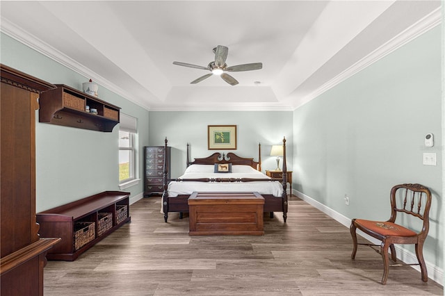 bedroom with crown molding, wood-type flooring, ceiling fan, and a raised ceiling