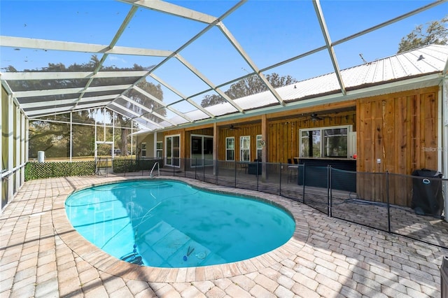 view of swimming pool featuring ceiling fan, a patio, and a lanai