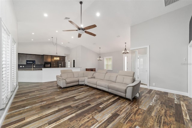 living room featuring high vaulted ceiling, dark hardwood / wood-style flooring, sink, and ceiling fan with notable chandelier