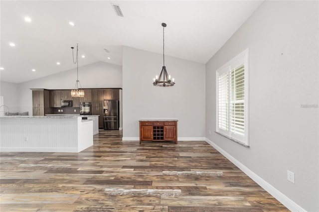 kitchen with dark brown cabinetry, appliances with stainless steel finishes, dark hardwood / wood-style floors, high vaulted ceiling, and hanging light fixtures