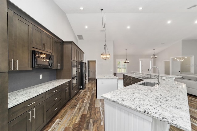 kitchen with stainless steel appliances, a large island with sink, sink, and vaulted ceiling